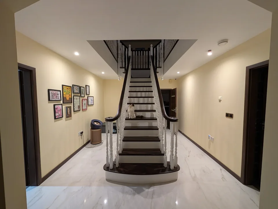 Light tiled hallway with a central staircase and dark wood detailing