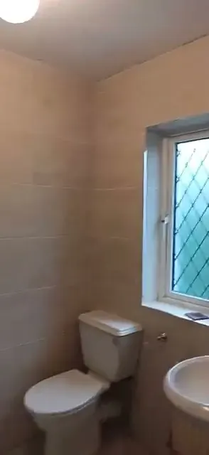 Toilet, wash basin and window with tiled walls in same finished bathroom