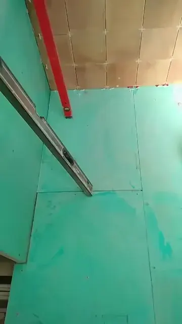 Green bathroom wall board installation with exposed upper wall and measuring level