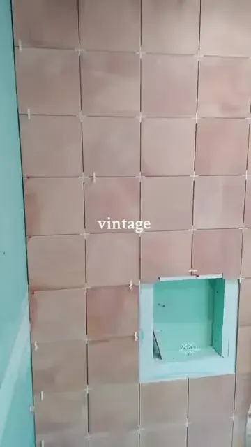 Pink square bathroom wall tiles and recessed niche with green board and spacers