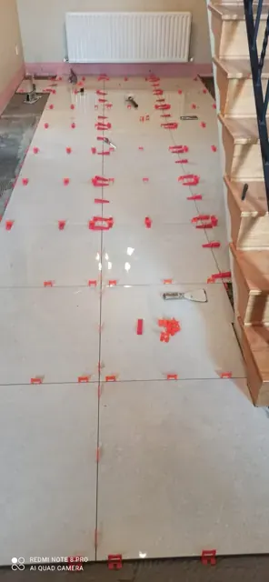 White floor tiles with red levelling clips during installation