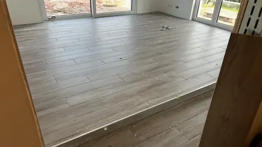 Wood-effect floor tiling in a sunlit room with visible levelling clips
